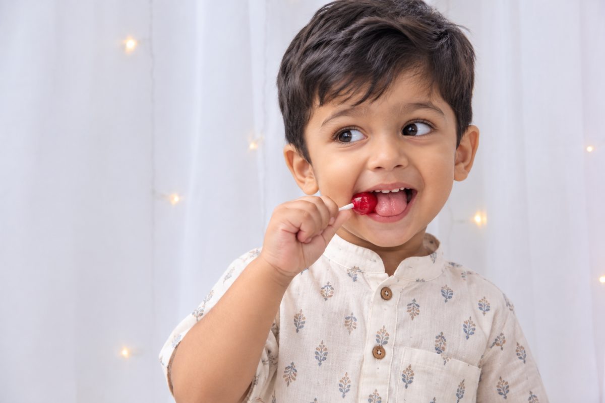Smiling boy enjoying a red lollipop