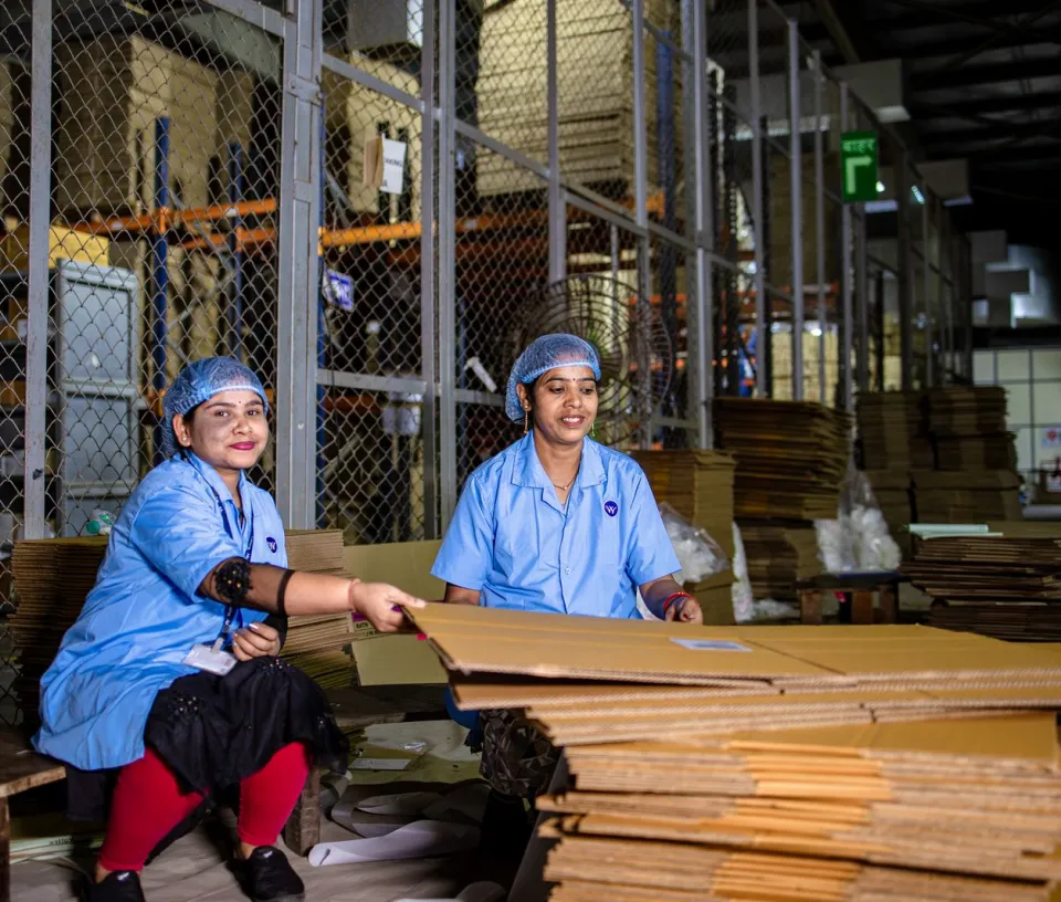 Workers in uniforms and hairnets preparing cartons for packing